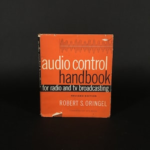 Könnte beinhalten: Ein orangefarbenes Buch mit dem Titel "Audio Control Handbook" für Radio und Fernsehen. Das Buch ist eine überarbeitete Ausgabe von Robert S. Oringel und wurde von Communication Arts Books herausgegeben.