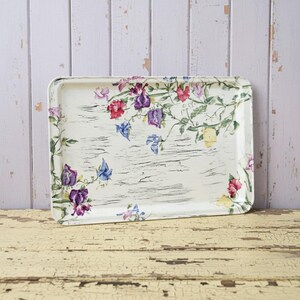 May include: A rectangular serving tray with a cream-coloured background featuring a distressed wood grain texture. The tray is decorated with a botanical print of colourful sweet pea flowers in shades of purple, pink, red, blue, and yellow.