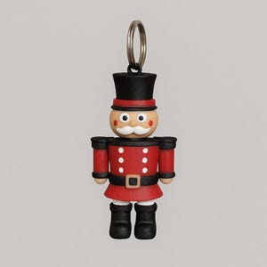 May include: A miniature toy soldier keychain. The figure is dressed in a red jacket with black accents, a black hat, and black boots. The face is tan with a white mustache. A silver key ring is attached to the top.