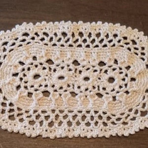 May include: A white crocheted oval doily with a delicate floral pattern.