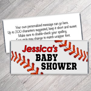 May include: A personalized baby shower candy bar wrapper with a baseball theme. The wrapper is white with red stitching and the text "Jessica's BABY SHOWER" in red and black. The top wrapper has text.