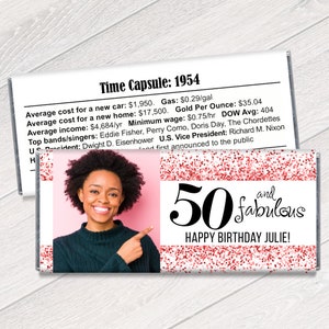 K&ouml;nnte beinhalten: Personalisierte Schokoriegelverpackung mit einem Foto einer Frau, dem Text "50 and fabulous" und "Happy Birthday Julie!" in Schwarz. Die Verpackung hat einen rosa Hintergrund mit roten Glitzerakzenten und einen Abschnitt mit historischen Fakten.
