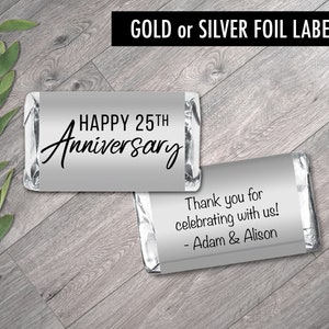 May include: Two silver foil labels for chocolate bars. The first label says "HAPPY 25TH Anniversary". The second label says "Thank you for celebrating with us! - Adam & Alison".