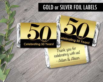 May include: Gold or silver foil labels with the number 50 in black text on a gold background. The text "Celebrating 50 Years!" is below the number. The labels are designed for chocolate bars.