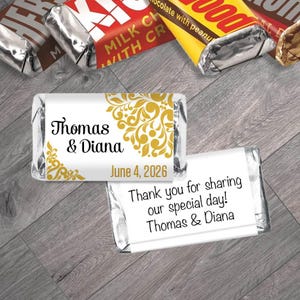 May include: Miniature chocolate bars with personalized labels. One label features the names "Thomas & Diana" and the date "June 4, 2026" with gold floral accents. Another label reads "Thank you for sharing our special day! Thomas & Diana."