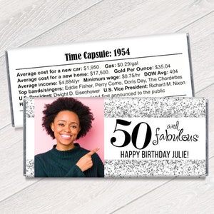 K&ouml;nnte beinhalten: Eine personalisierte Schokoriegelverpackung mit einem Foto einer Frau, dem Text "50 and fabulous" und "Happy Birthday Julie!". Die Verpackung hat ein silbernes Glitzerdesign und einen Abschnitt mit historischen Fakten von 1954.