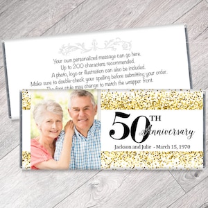 May include: A personalized candy bar wrapper for a 50th anniversary. The design features a photo of a couple, gold glitter accents, and the text "50th Anniversary" with the names and date.