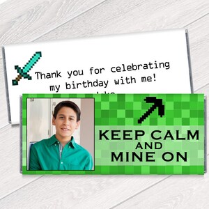 May include: A green and black Minecraft themed chocolate bar wrapper with a picture of a young person and the text "Keep Calm and Mine On".
