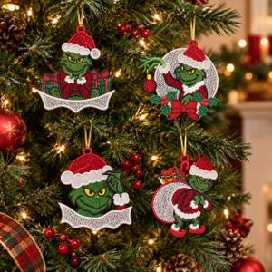 May include: Four embroidered Christmas ornaments featuring a green character in a red Santa hat. One shows the character with gifts, one in a circular frame with a red ornament, one with a blank white banner, and one carrying a large sack of gifts.