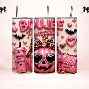 May include: A cylindrical tumbler with a straw featuring a pink design with the text "BOUJEE Pumpkin" and "Spooky but Caffeinated". The graphic includes a pink pumpkin wearing heart-shaped sunglasses and a leopard print bow, a pink quilted handbag, bats, and hearts.