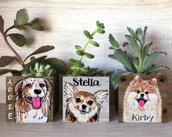May include: Three wooden planters with succulents, each featuring a different dog portrait. The first planter says "Addie", the second says "Stella", and the third says "Kirby". Each dog has a pink tongue.