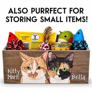 May include: Wooden storage box with a painted image of two cats, "Kitty Mark" and "Bella". The box is filled with cat toys, treats, and a can of food. Text at the top reads "ALSO PURRFECT FOR STORING SMALL ITEMS!"