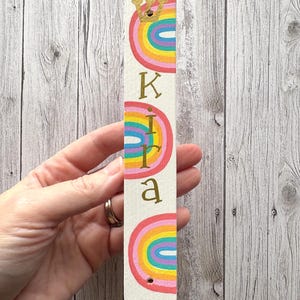 A hand holding a colorful, personalized name tag with a rainbow design.