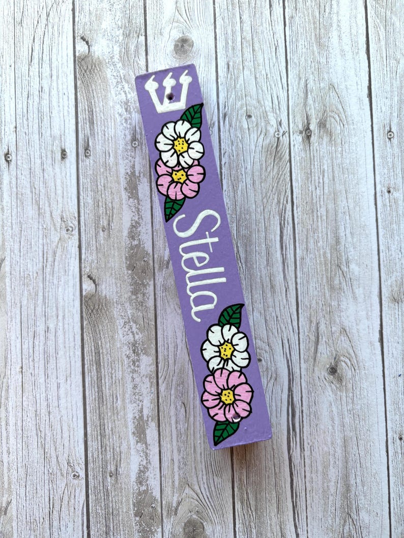 A purple sign with a crown and flowers on it, placed on a wooden surface.