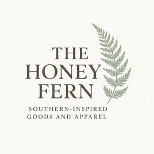 K&ouml;nnte beinhalten: Das Honey Fern-Logo auf cremefarbenem Hintergrund. Der Text lautet "THE HONEY FERN" in einer dunkelbraunen Serifenschrift, darunter "SOUTHERN-INSPIRED GOODS AND APPAREL". Rechts ist eine gr&uuml;ne Farnillustration.