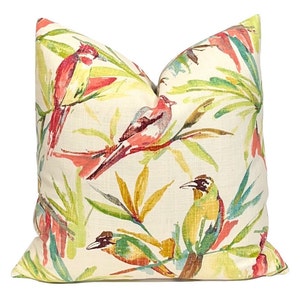 May include: A cream-colored pillow cover with a tropical print featuring red, pink, yellow, and green birds and leaves.