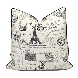 May include: Black and white throw pillow with a Parisian theme. The pillow features an Eiffel Tower, stamps, and the word "Paris".