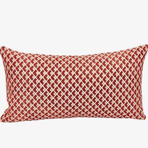 Pode incluir: Almofada decorativa retangular com um padrão de losangos vermelhos e creme. A almofada tem uma aparência texturizada e é projetada para uso decorativo. A almofada tem aproximadamente 50 cm de comprimento.