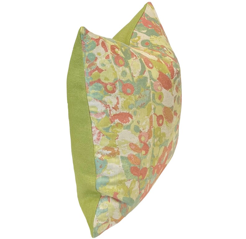 Op de afbeelding: Een groen en cr&egrave;mekleurig kussen met een bloemenpatroon in tinten roze, oranje en groen.