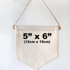 May include: A white canvas pennant banner with the text "5" inches by "6" inches (12cm x 15cm) printed in black.