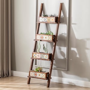 Puede incluir: Una estantería de escalera de madera marrón oscuro con cuatro jardineras rectangulares. Cada jardinera presenta azulejos coloridos y estampados y contiene varias plantas, incluyendo suculentas y cactus. La escalera se apoya contra una pared gris claro.