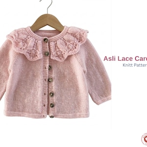 May include: A light pink knitted cardigan with a lace collar and wooden buttons. The long-sleeved sweater is displayed on a wooden hanger. The text "Asli Lace Cardigan Knitt Pattern" is visible on the right side of the image.