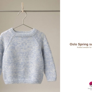 Könnte beinhalten: Ein hellblau-weiß gesprenkelter Strickpullover für Kinder hängt an einem Metallbügel. Der Pullover hat lange Ärmel und einen Rundhalsausschnitt. Der Text "Oslo Spring sweater" und "Knitted sweater for children" ist sichtbar.