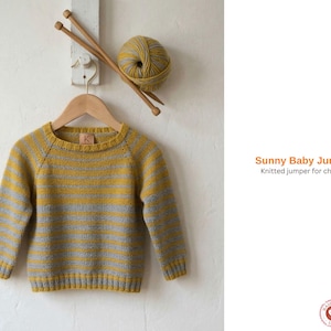 Puede incluir: Un jersey de bebé de punto a rayas amarillas y grises colgado de una percha de madera. Se muestra una madeja de lana y agujas de tejer encima. El texto dice "Sunny Baby Jumper" y "Knitted jumper for children."