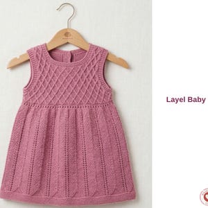Puede incluir: Vestido de bebé sin mangas, rosa empolvado, con un patrón de diamantes en el corpiño y canalé vertical en la falda. El vestido se muestra en una percha de madera. El texto "Layel Baby Dress" es visible.