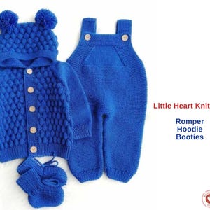 May include: A knitted blue baby set comprising a romper, hooded jacket, and booties. The jacket has a button-up front and a textured pattern. The hood features two pom-poms. The set is displayed with the text "Little Heart Knitt Set".