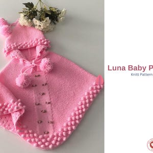 Puede incluir: Un poncho y gorro a juego para bebé, de punto rosa, con pompones. El poncho tiene cierre de botones y un ribete de punto de arroz texturizado. El texto "Luna Baby Poncho" y "Knitt Pattern" son visibles.