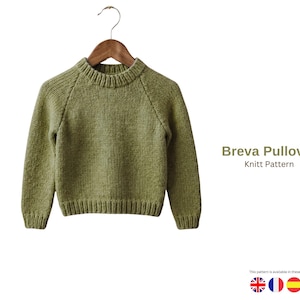 May include: A green pullover sweater with a ribbed neckline, cuffs, and hem, hanging on a wooden hanger. The sweater has raglan sleeves and is made of a textured knit fabric. The text "Breva Pullover Knitt Pattern" is visible.
