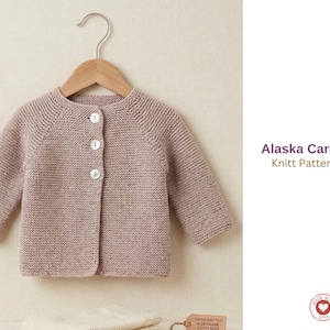 Puede incluir: Un cárdigan de bebé de color malva claro con tres botones blancos, colgado de una percha de madera. El texto "Alaska Cardigan Knitt Pattern Set" es visible a la derecha. El cárdigan es de punto.