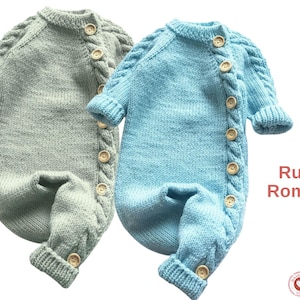 Puede incluir: Dos peleles de bebé de punto, uno gris claro y otro azul claro, con botones de madera y detalles de punto trenzado. El texto "Rupa Romper" es visible. Estos peleles acogedores son perfectos para recién nacidos.