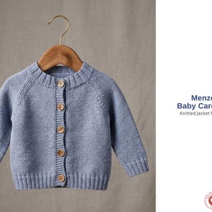 Pode incluir: Um cardigan azul claro para bebé com botões de madeira, pendurado num cabide de madeira. O casaco de malha tem mangas compridas e punhos e bainha canelados. O texto diz "Menzo Baby Cardigan Knitted jacket for baby".
