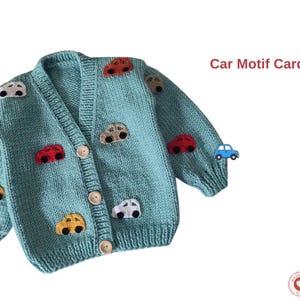 Può includere: Cardigan lavorato a maglia blu chiaro con scollo a V e chiusura con bottoni. Il maglione è decorato con applicazioni di auto di vari colori. Il testo "Car Motif Cardigan" è visualizzato in alto a destra.