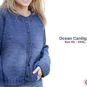 May include: A blue knit cardigan with a round neckline and button closure. The sweater has long sleeves and is labeled "Ocean Cardigan" with size options from XS to XXXL. The cardigan is a medium blue color.