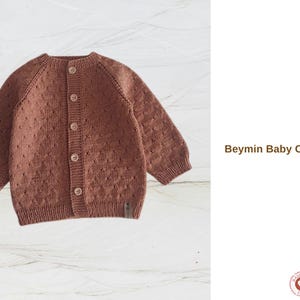 May include: A brown baby cardigan with a button-up front and long sleeves. The knitted sweater has a textured pattern and is labeled "Beymin Baby Cardigan". The garment is handmade.