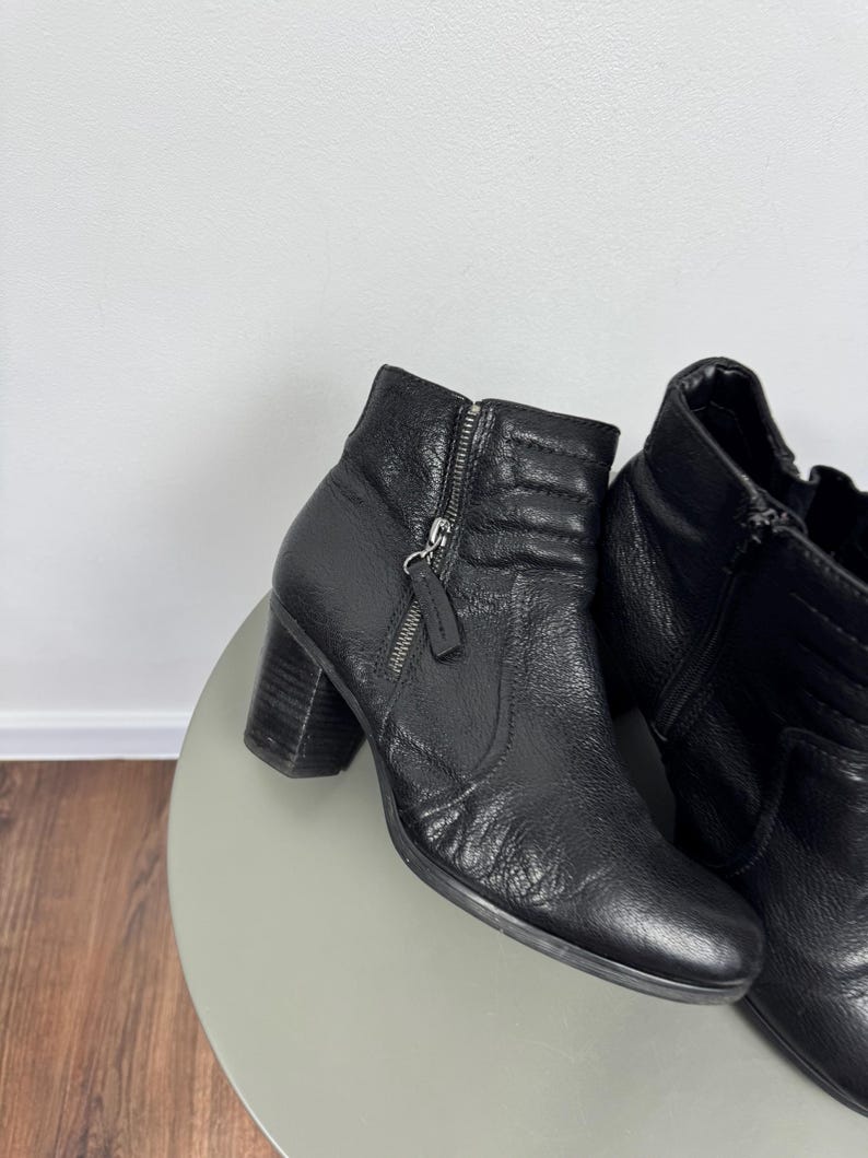 Pu&ograve; includere: Stivaletti in pelle nera con tacco a blocco. Gli stivali hanno una chiusura con zip laterale e pelle strutturata. L'altezza del tacco &egrave; di circa 6,35 cm.