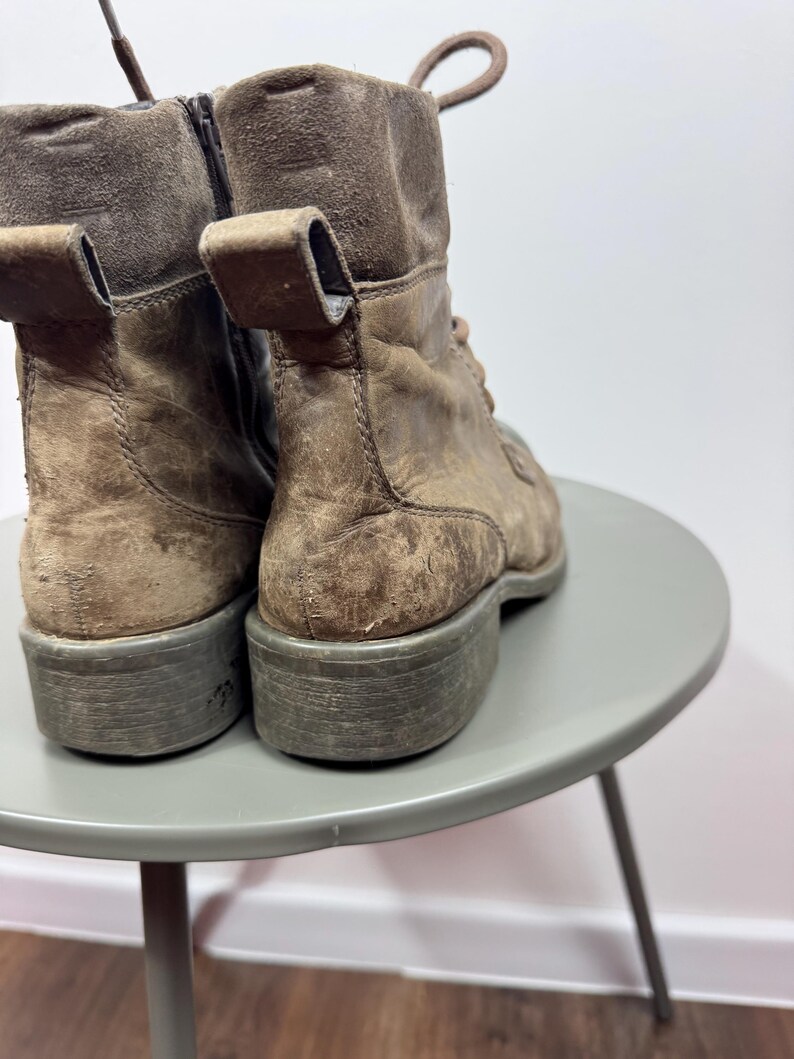 K&ouml;nnte beinhalten: Ein Paar braune Lederstiefeletten mit Used-Optik, Schn&uuml;rung vorne, seitlichem Rei&szlig;verschluss, Zuglasche an der Ferse und einer dicken, flachen Gummisohle. Die Stiefel verf&uuml;gen &uuml;ber einen strukturierten, wildlederartigen Schaftabschluss.