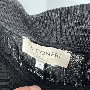 May include: Close-up of a black garment with a ribbed waistband. The label reads "FALCONERI made in Italy" with a size "S" tag. The fabric has a subtle metallic sheen.