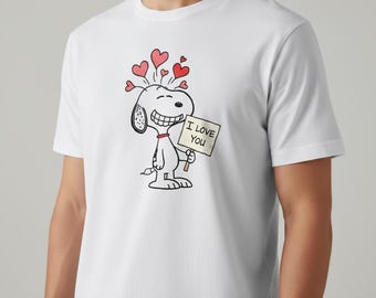 Könnte beinhalten: Weißes T-Shirt mit einem Cartoon-Design von Snoopy, der ein Schild mit der Aufschrift "I LOVE YOU" hält und rote Herzen über dem Kopf hat. Das Design ist in Schwarz, Rot und Weiß gehalten.