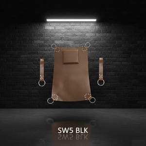 A brown leather sling with a square headrest and metal rings. Two leather straps with metal rings are on either side. The product is against a black brick wall. The text "SW5 BLK" is at the bottom.