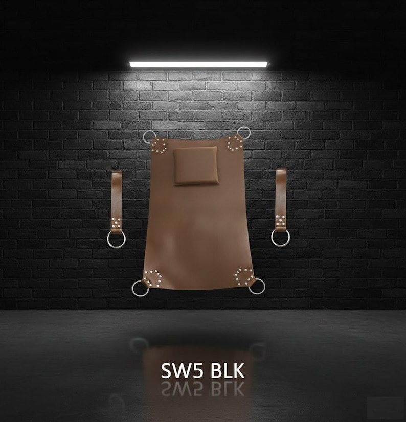 A brown leather sling with a square headrest and metal rings. Two leather straps with metal rings are on either side. The product is against a black brick wall. The text "SW5 BLK" is at the bottom.