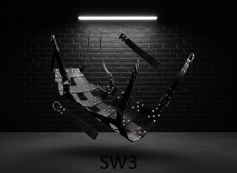 A black leather swing with silver rivets and straps, suspended in a dark room. The swing has a curved seat and multiple attachment points. The image includes the text "SW3" at the bottom.