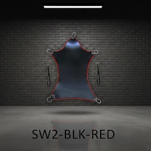 Black, star-shaped sling with red edging and metal rings. The sling has two black straps and is suspended in a room with a brick wall. The text "SW2-BLK-RED" is at the bottom.