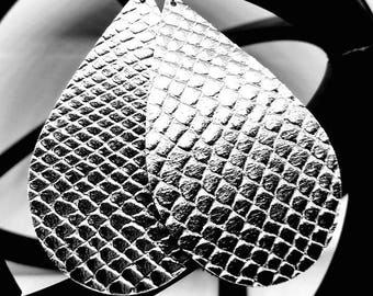 May include: A pair of silver teardrop-shaped earrings with a snakeskin pattern.