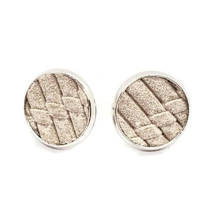 May include: A pair of silver stud earrings with a woven pattern on the front. The earrings are round and have a smooth, polished finish.