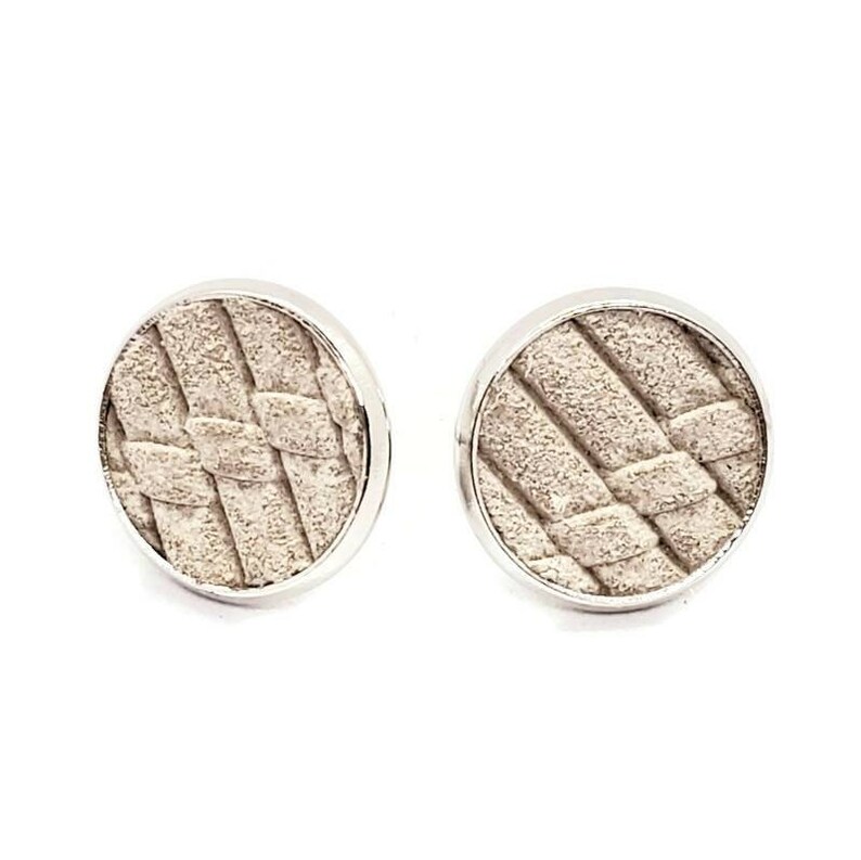 May include: A pair of silver stud earrings with a woven pattern on the front. The earrings are round and have a smooth, polished finish.