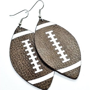 May include: A pair of brown leather earrings shaped like footballs with white stitching and stripes.